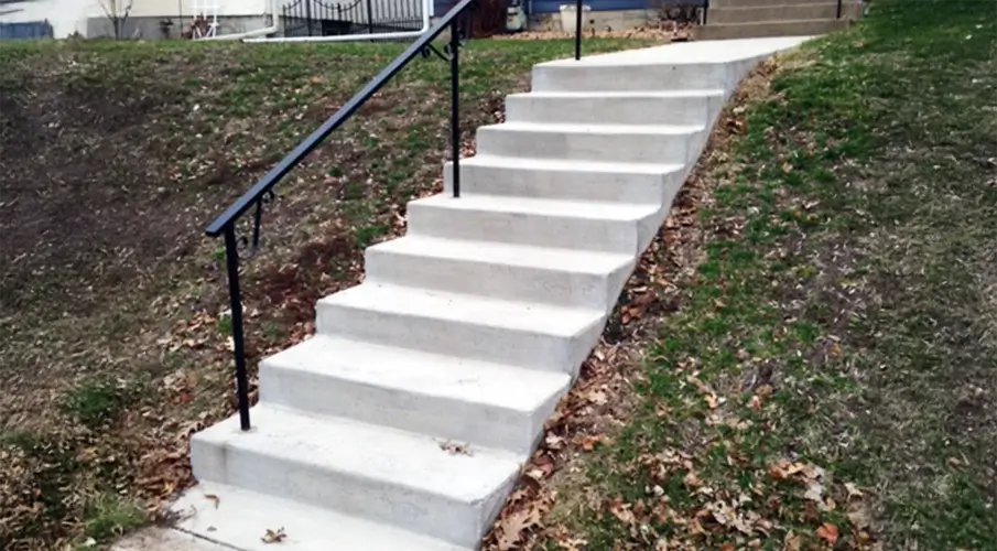 New poured concrete stairs with handrail on a sloped Lakeland yard